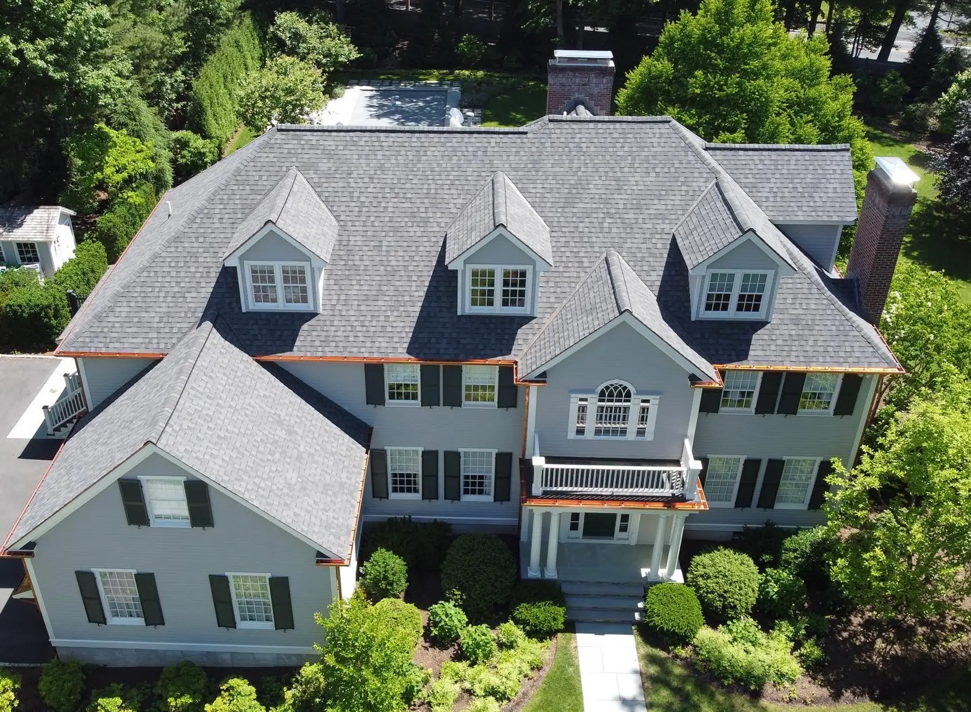 Aerial view of a completed gray architectural shingle roof with copper gutters on a Greater Boston colonial