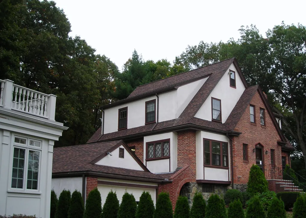Brick and stucco Tudor home with a newly completed brown shingle roof