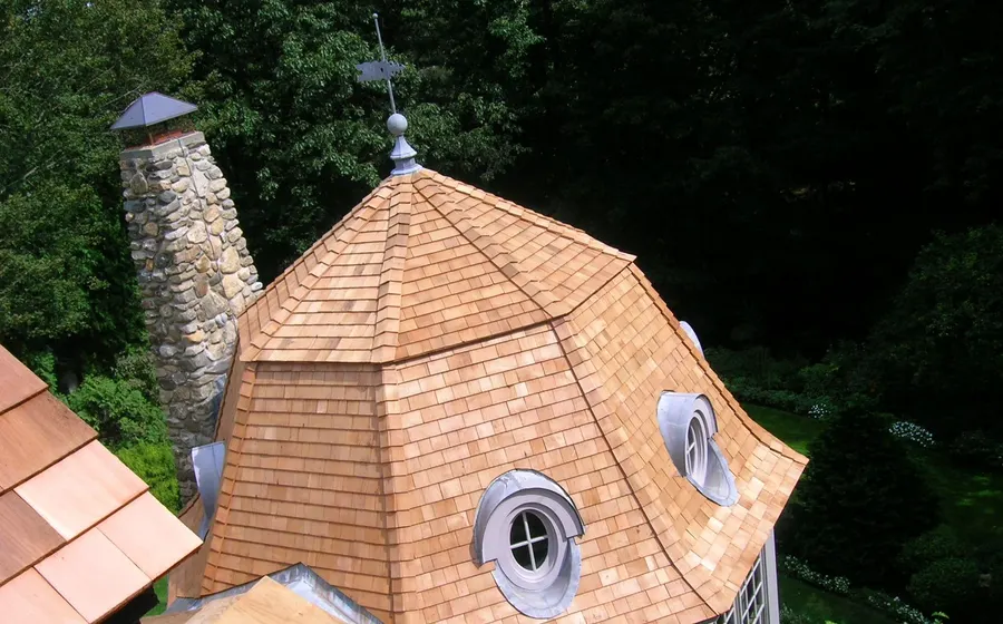 Octagonal turret roof clad in new cedar shingles with lead-coated copper flashing around oval dormer windows